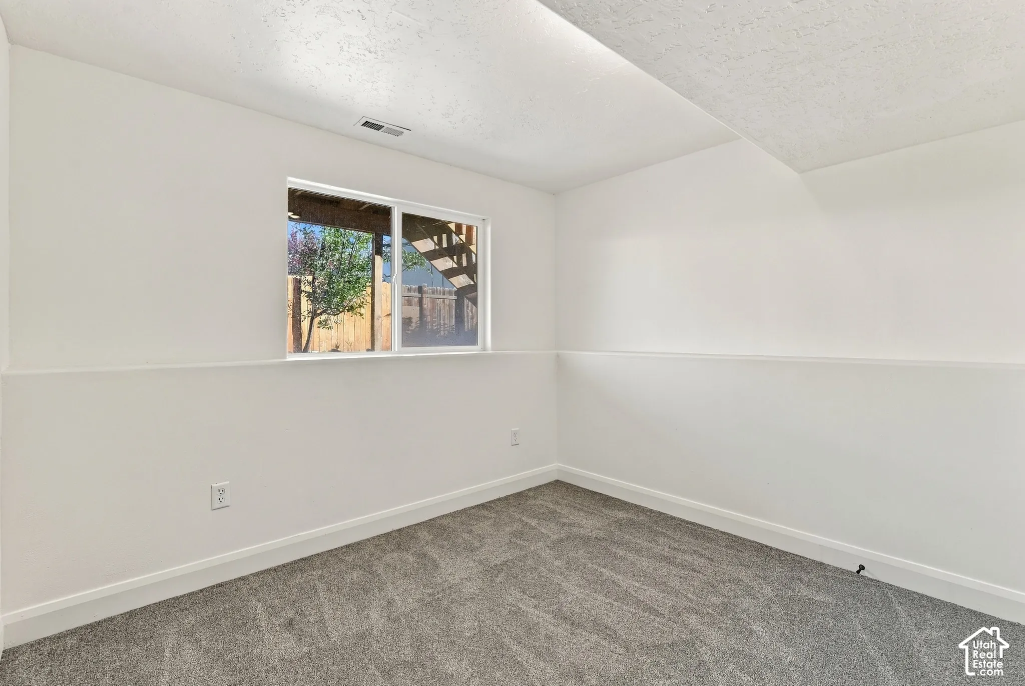 Interior room featuring neutral wall-to-wall carpeting, white walls, and a sliding window