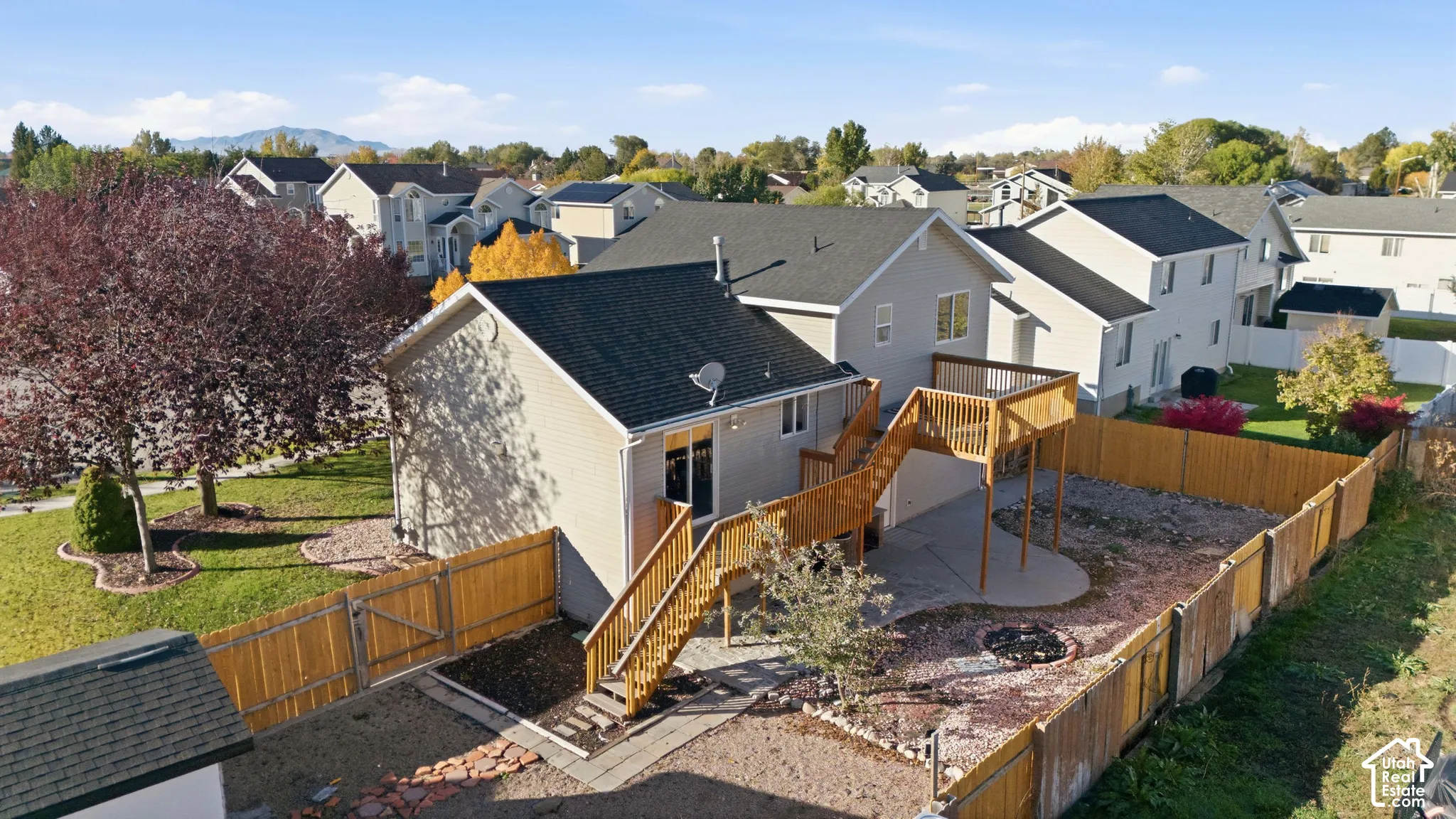 Exterior featuring siding, elevated wood deck with stairs, fenced backyard, concrete patio, and mountain backdrop