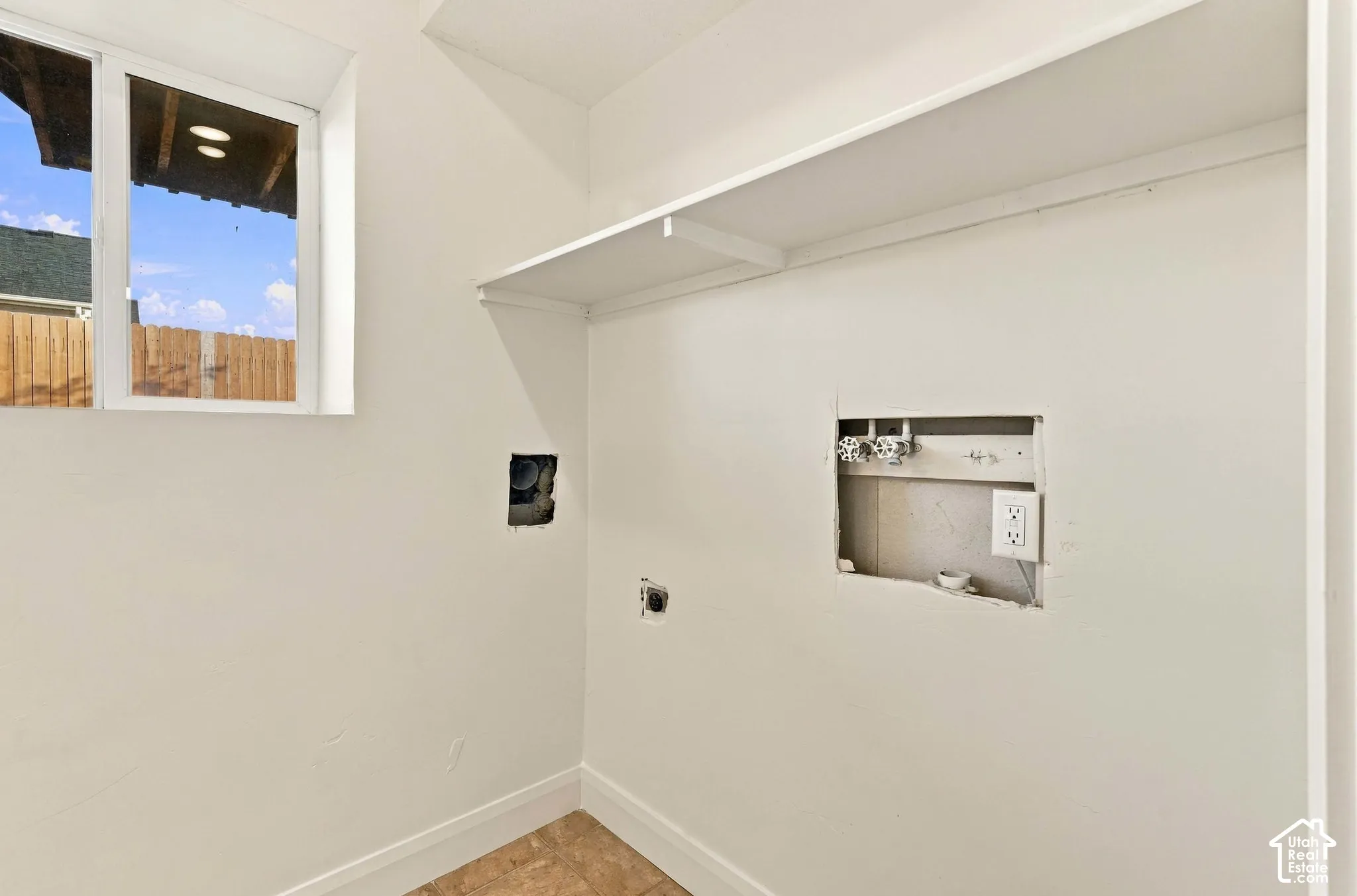 Utility space featuring a window, built-in shelving, and dedicated water and electrical hookups