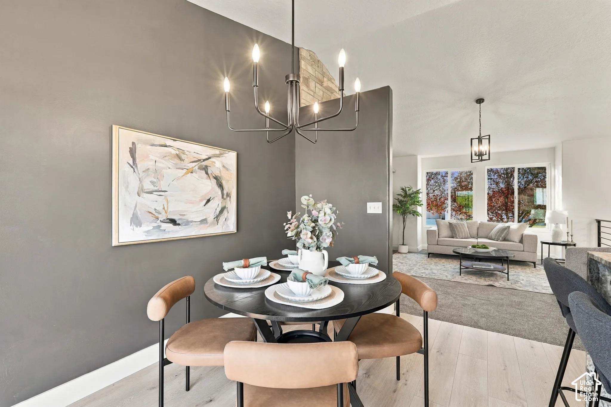 Dining area featuring a contemporary multi-arm chandelier, light-toned wood-finish flooring, and a decorative stone-finish accent wall
