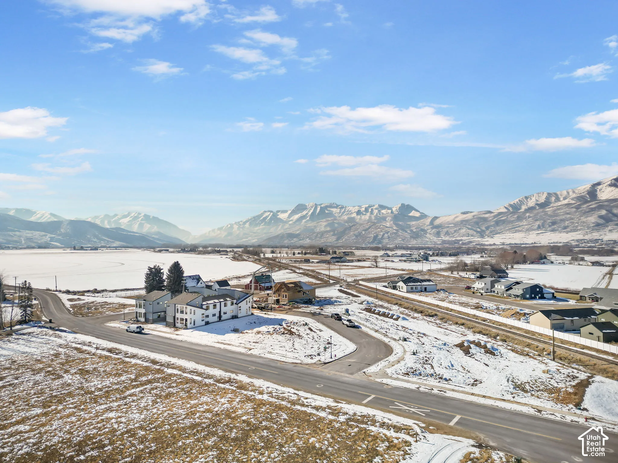 Aerial perspective featuring expansive mountain range backdrop, open terrain, and paved roadway infrastructure