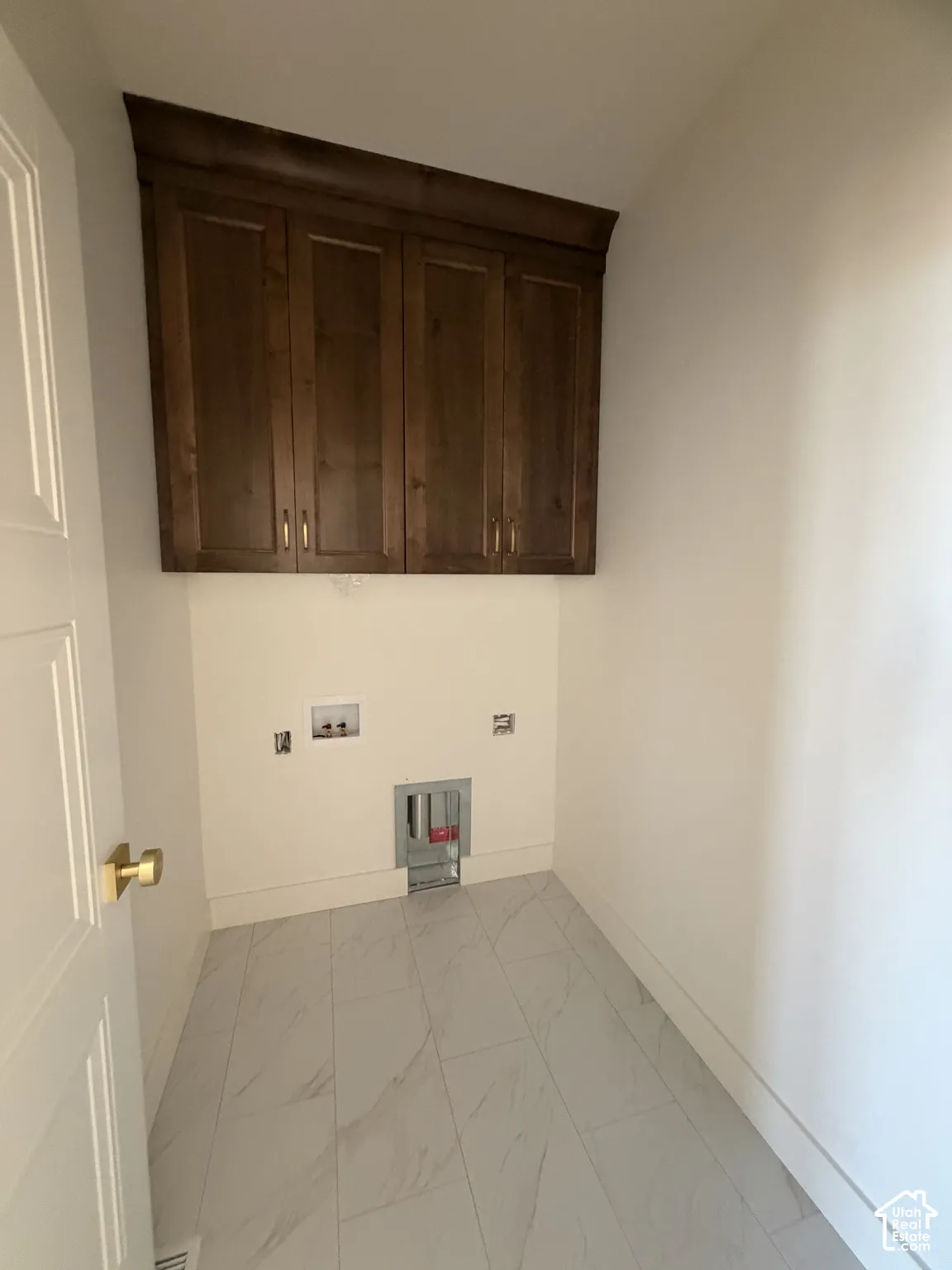 Utility area featuring custom-stained cabinetry, crown molding, and large-format porcelain tile flooring