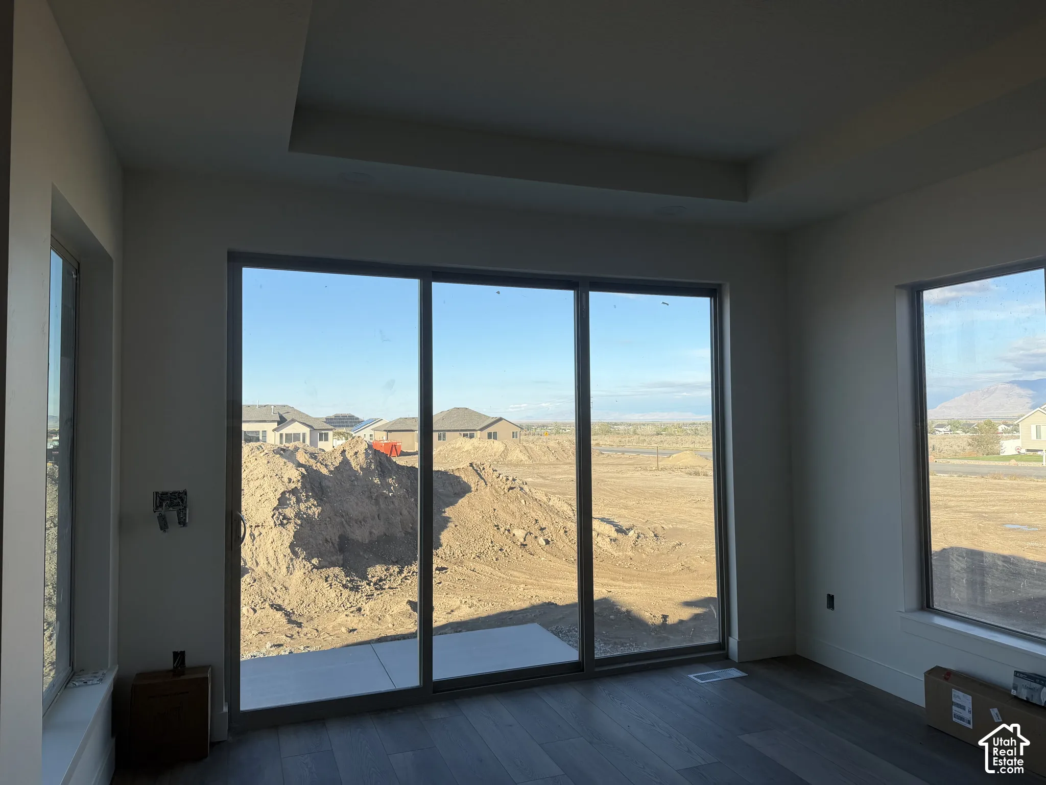 Interior space featuring a recessed tray ceiling, wood-finish flooring, and large sliding glass doors providing natural light