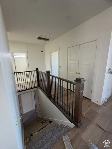 Landing area featuring wood-finish flooring, recessed lighting, and a staircase with stained wood newel posts and metal balusters