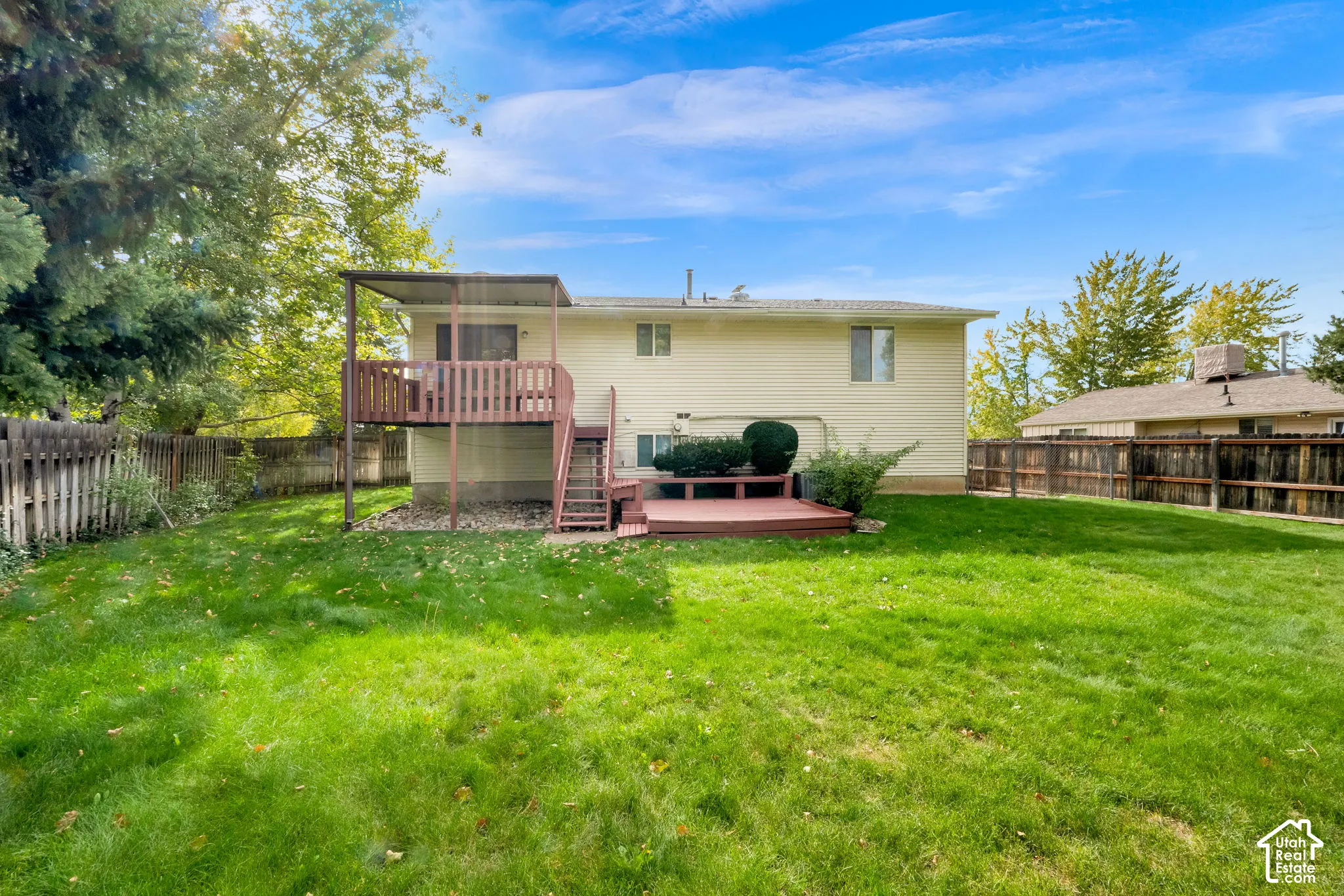 Backyard featuring a lawn, mature trees, wood-style deck, covered elevated deck, and wood fencing