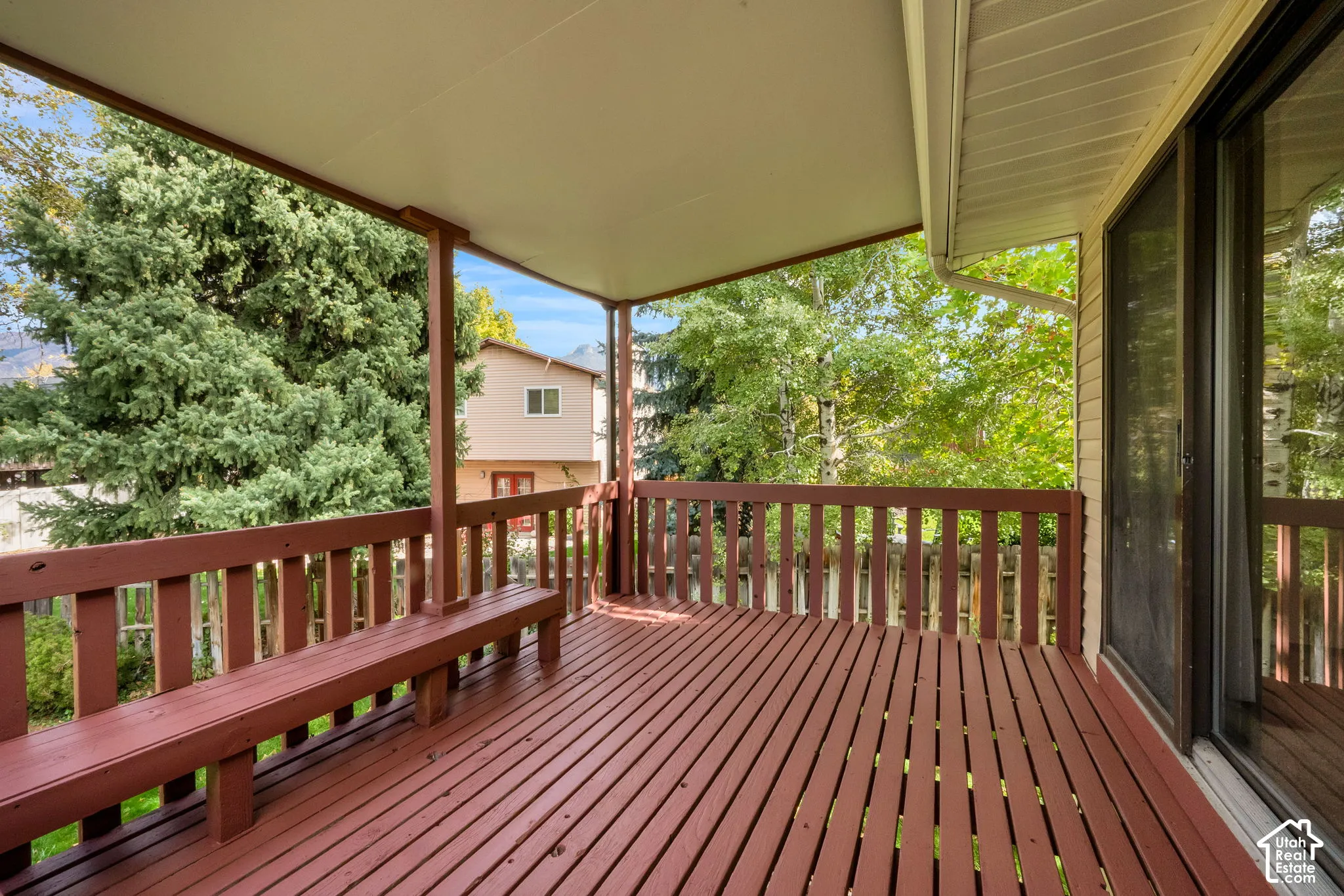Covered deck featuring painted wood decking, built-in bench seating, a wood railing, and a solid roof canopy