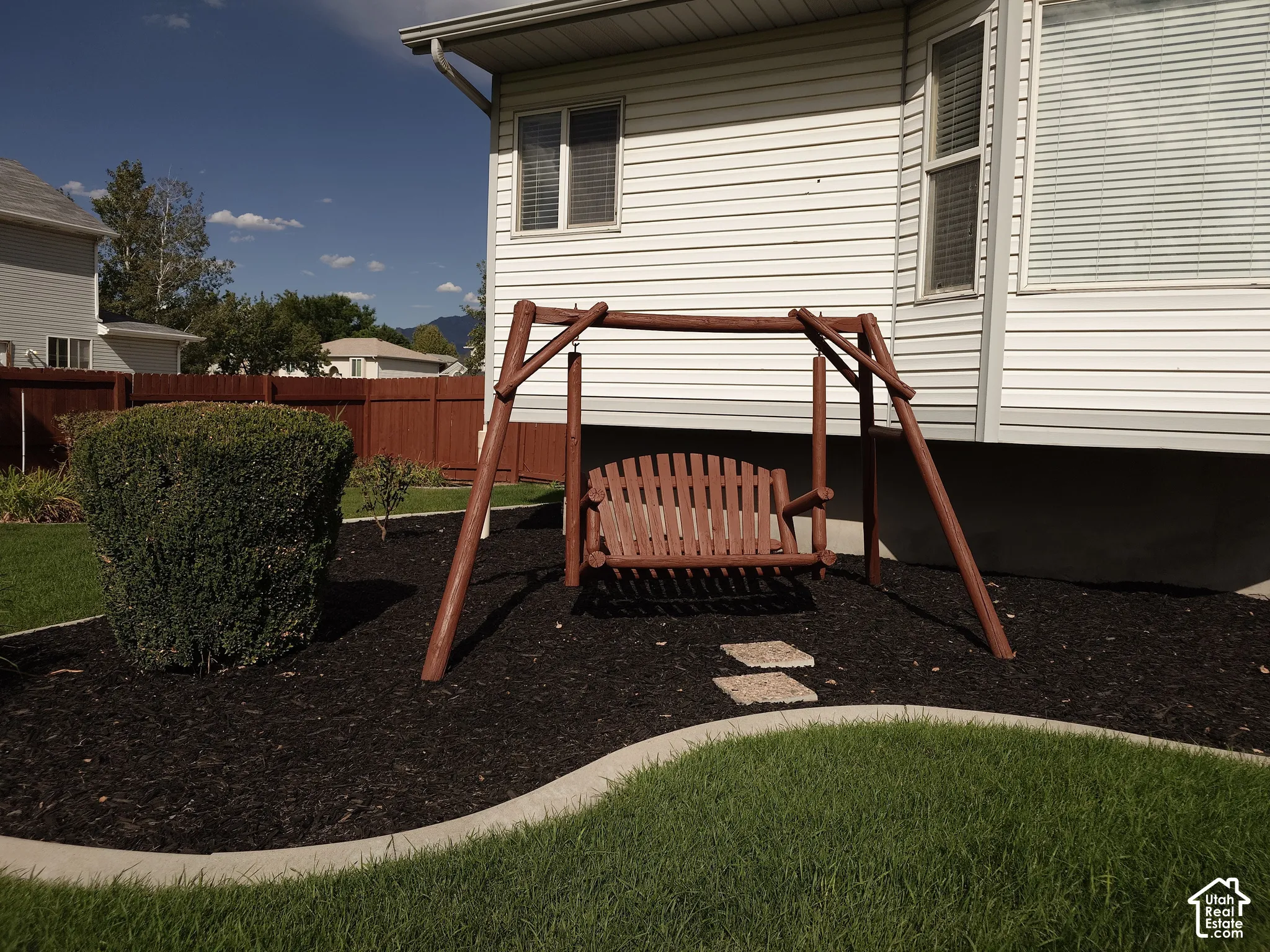 Vinyl siding exterior with a manicured lawn, curved concrete curbing, and a wood privacy fence