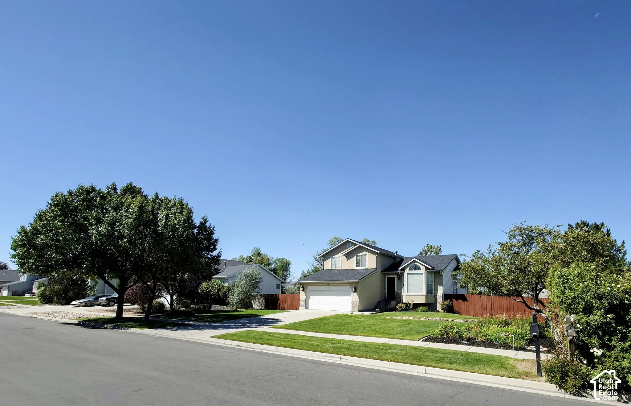 Two-story residence featuring a multi-textured exterior, gabled roofline, concrete driveway, attached two-car garage, and established front landscaping