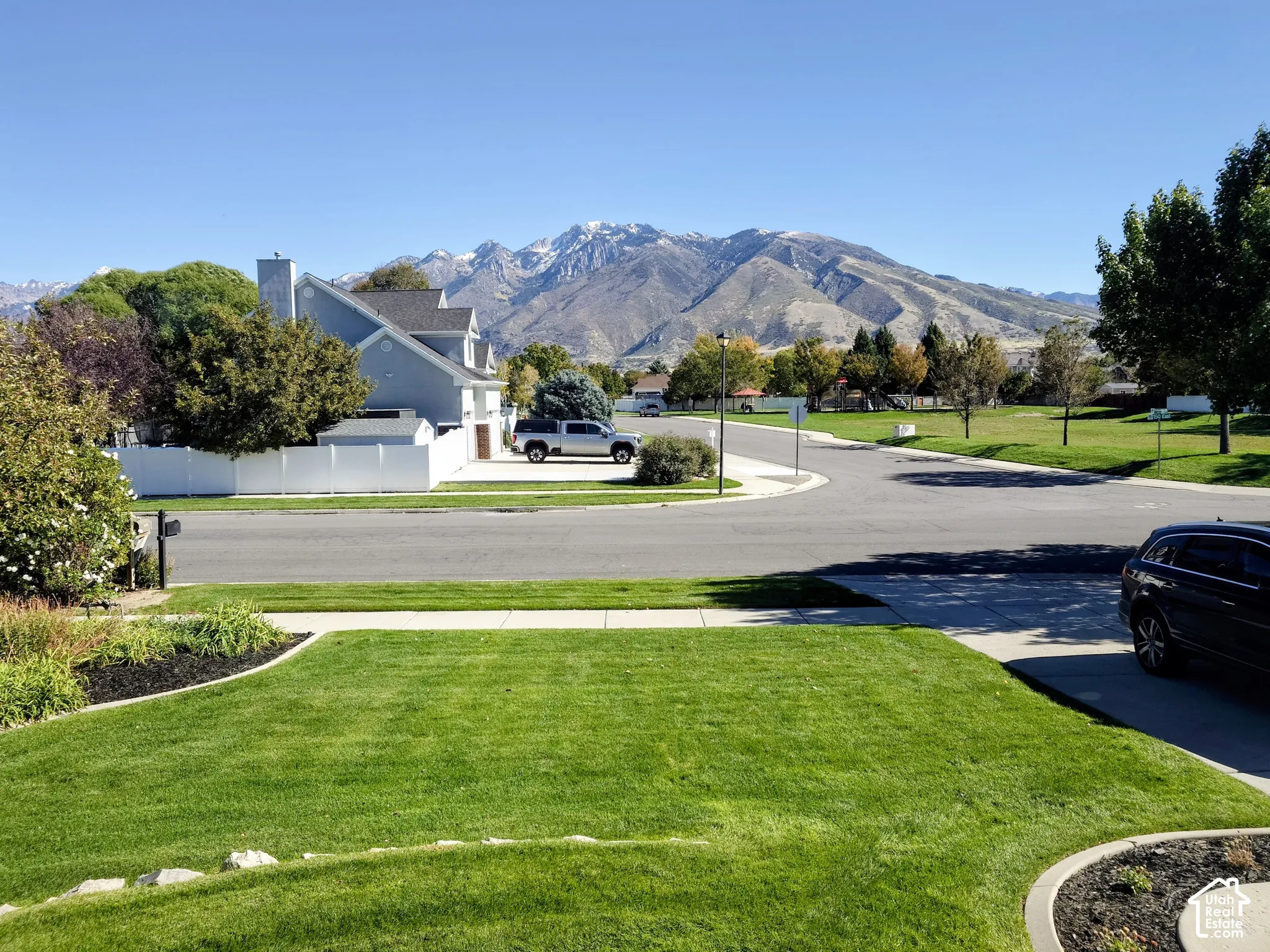 Residential streetscape featuring a groomed front lawn with landscape edging and mountain scenery
