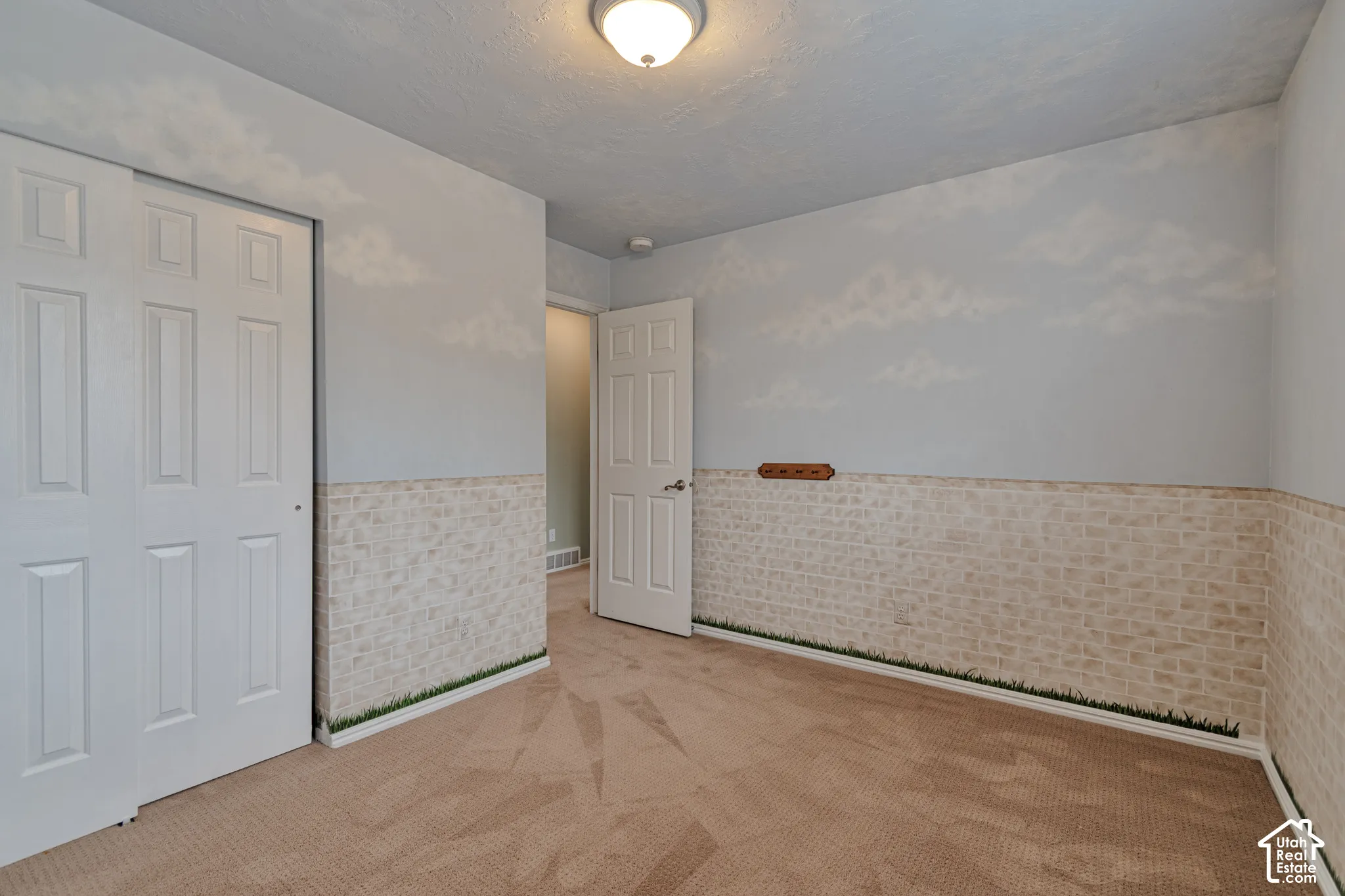 Room featuring wall-to-wall carpeting, textured wainscoting, ceiling-mounted light fixture, and two-panel interior doors