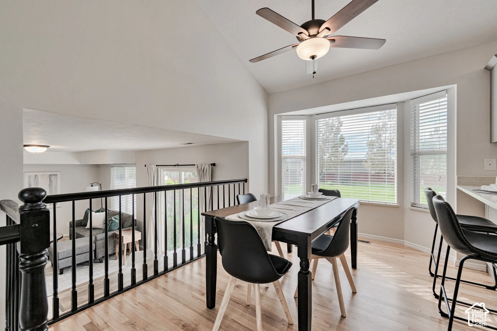 Vaulted ceilings, wood-finish flooring, bay window, and matte black railing