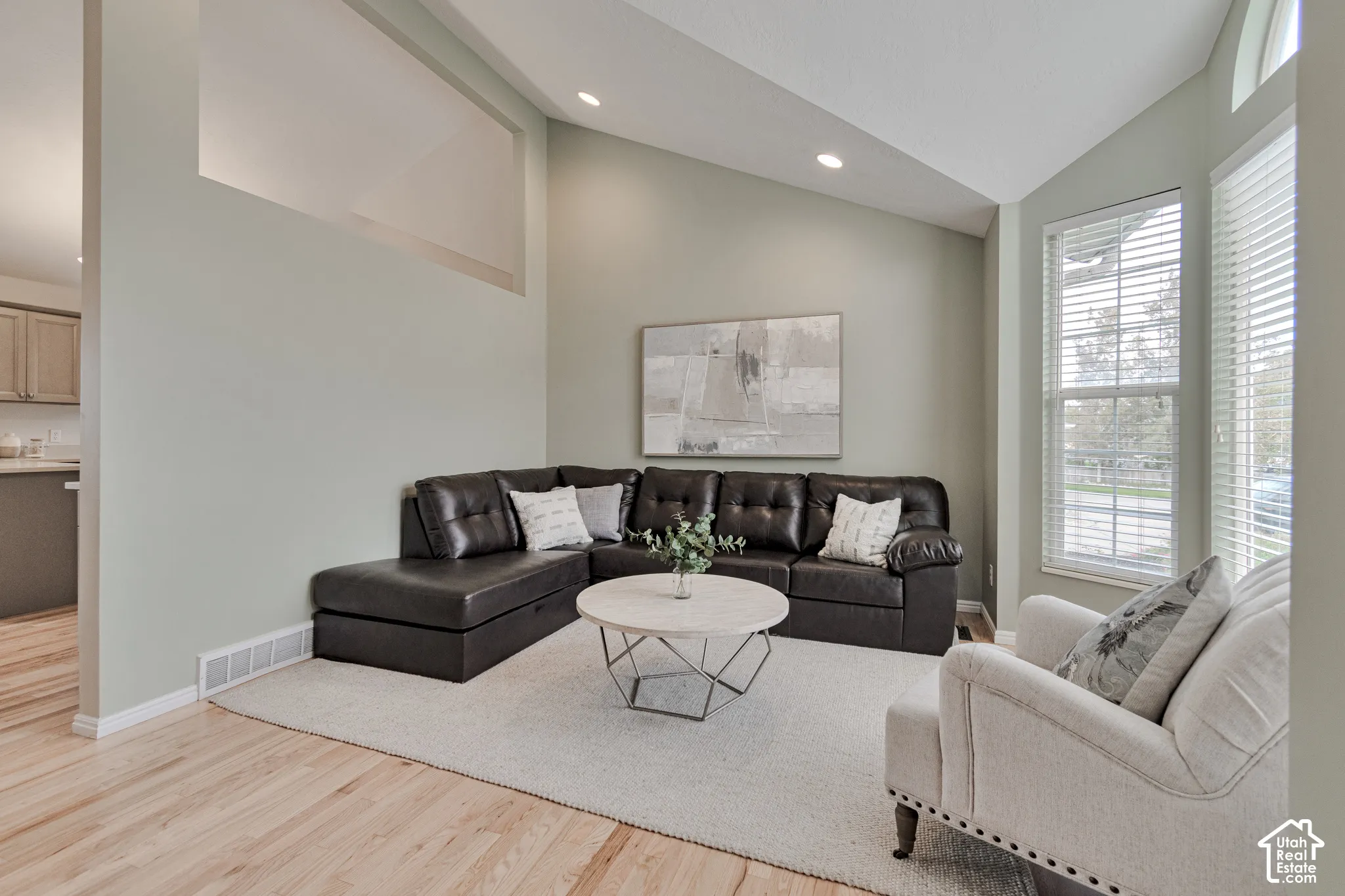 Vaulted ceilings, wood-finish flooring, recessed lighting, and large windows with horizontal blinds