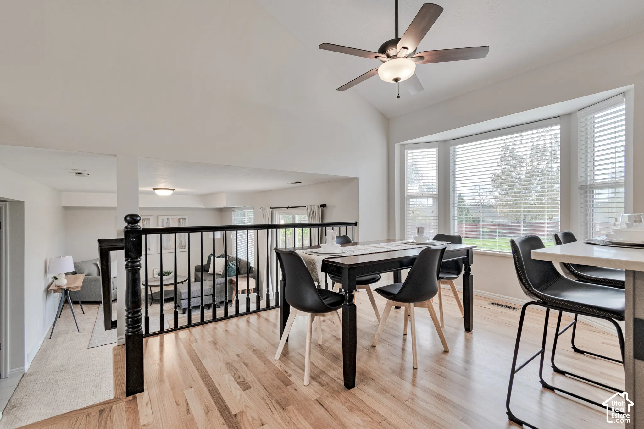 Vaulted ceilings, wood-finish flooring, bay window, and black metal spindle railing