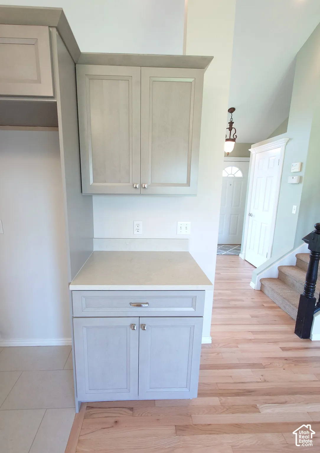 Built-in cabinetry featuring shaker-style doors, stone-finish countertops, wood-finish flooring, and a decorative pendant light fixture