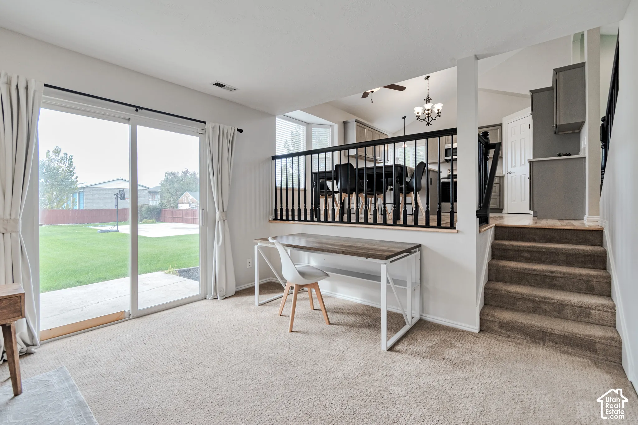 Sliding glass door, neutral carpeting, elevated railing with black balusters, and staircase with carpeted treads
