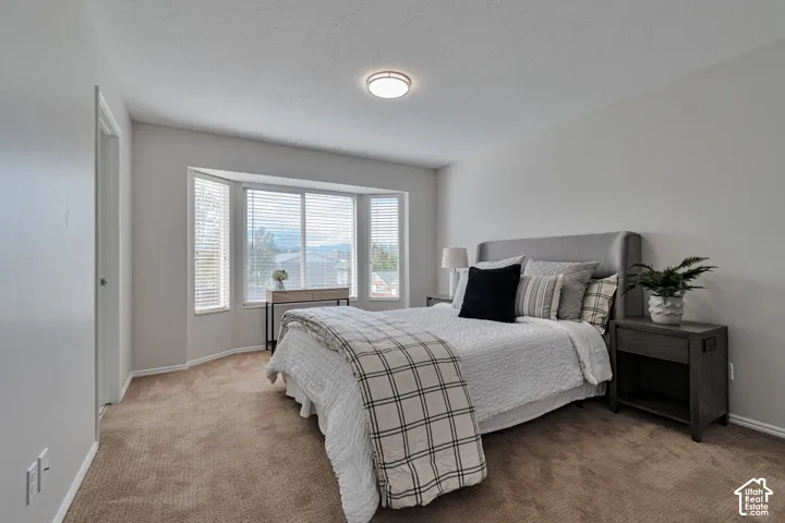 Neutral interior featuring neutral wall paint, wall-to-wall carpeting, a three-panel bay window, and a flush-mount overhead light fixture