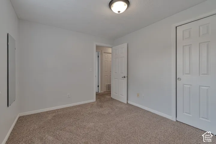 Room featuring neutral carpeting, six-panel interior doors, and a flush-mount ceiling light fixture