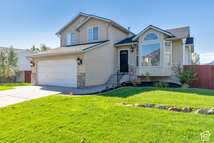 Two-story residence featuring a stucco exterior, stone accents, a bay window with an arched transom, a two-car garage, and an attached entry staircase