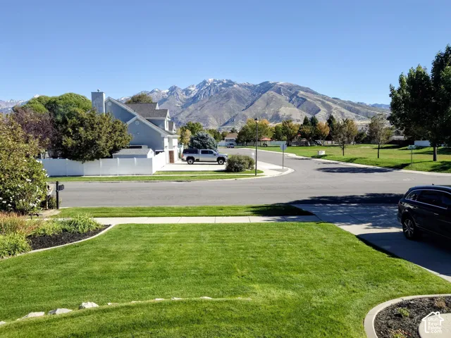 Residential streetscape featuring a groomed front lawn with landscape edging and mountain scenery