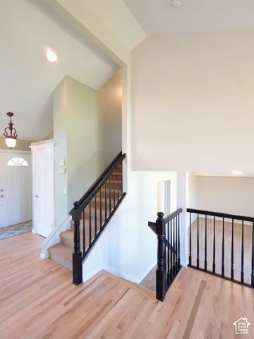 Entryway featuring vaulted ceilings, wood-finish flooring, and a staircase with decorative black railings