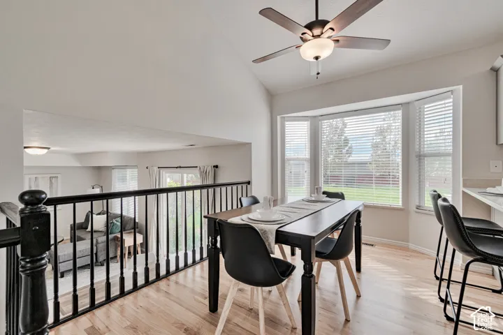 Vaulted ceilings, wood-finish flooring, bay window, and matte black railing