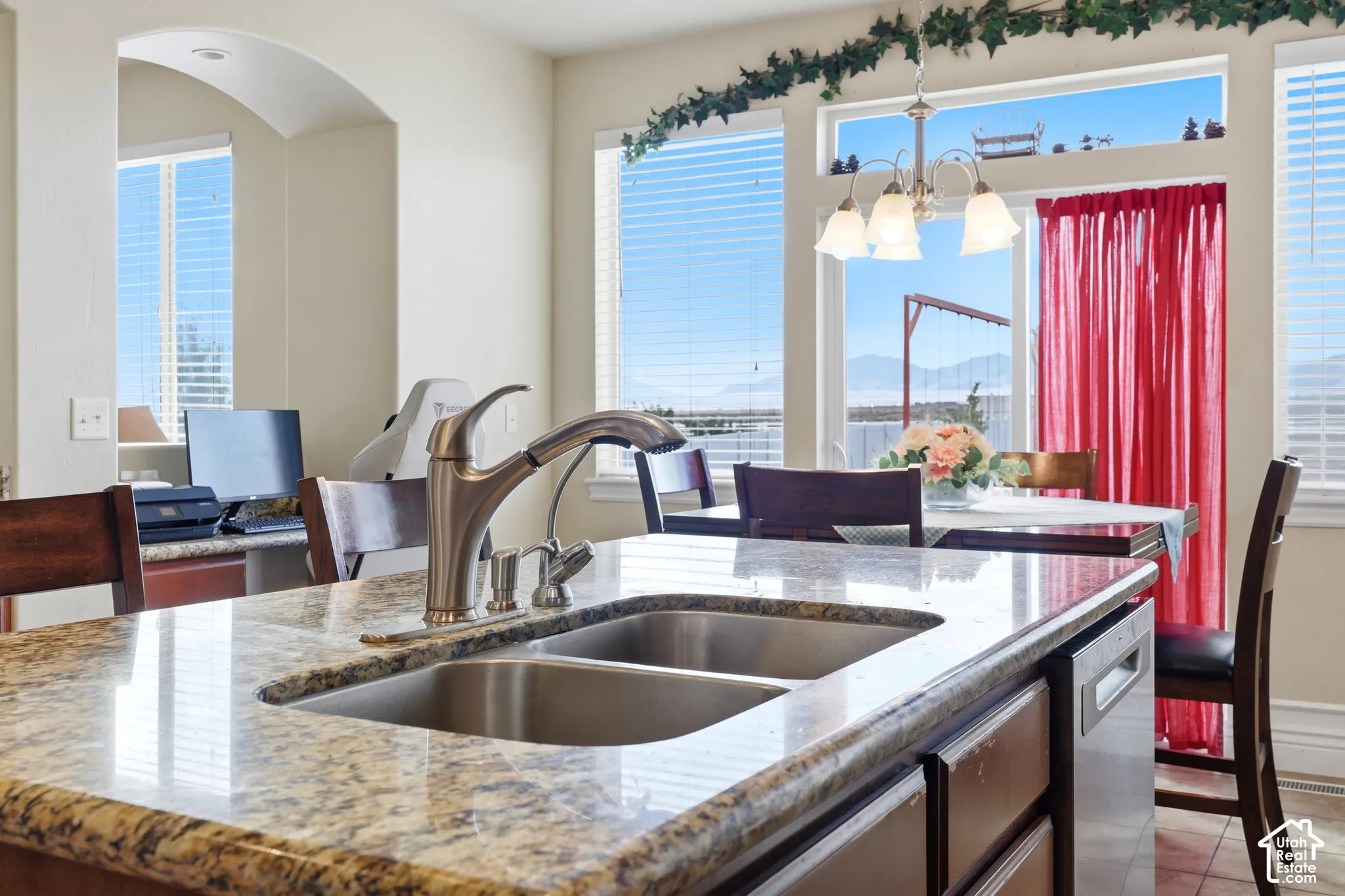 Kitchen island featuring a dual-basin stainless steel sink, pull-down faucet, and stone-finish countertop