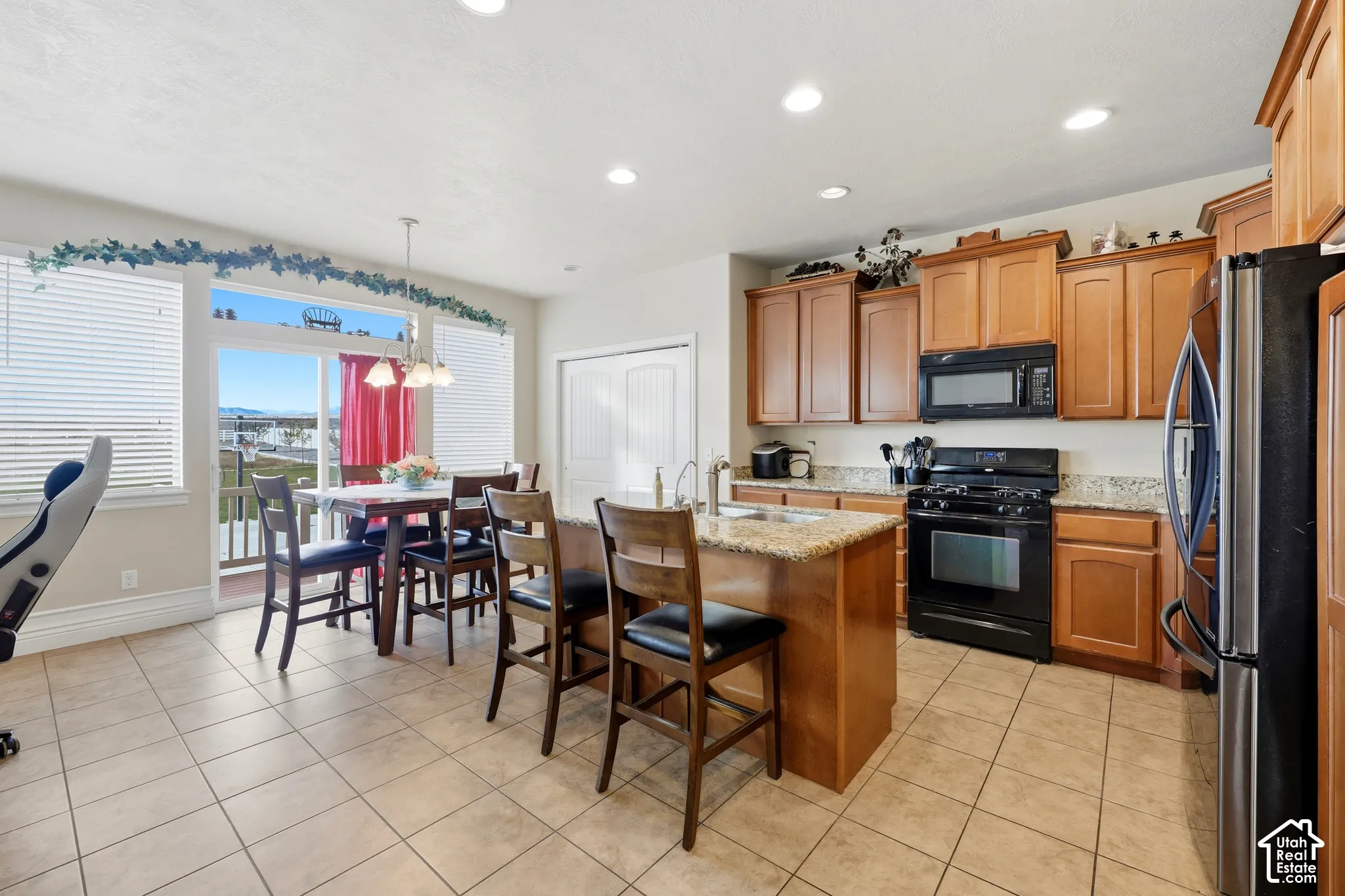 Kitchen featuring wood cabinetry, stone countertops, a center island with a sink, recessed lighting, and tile flooring