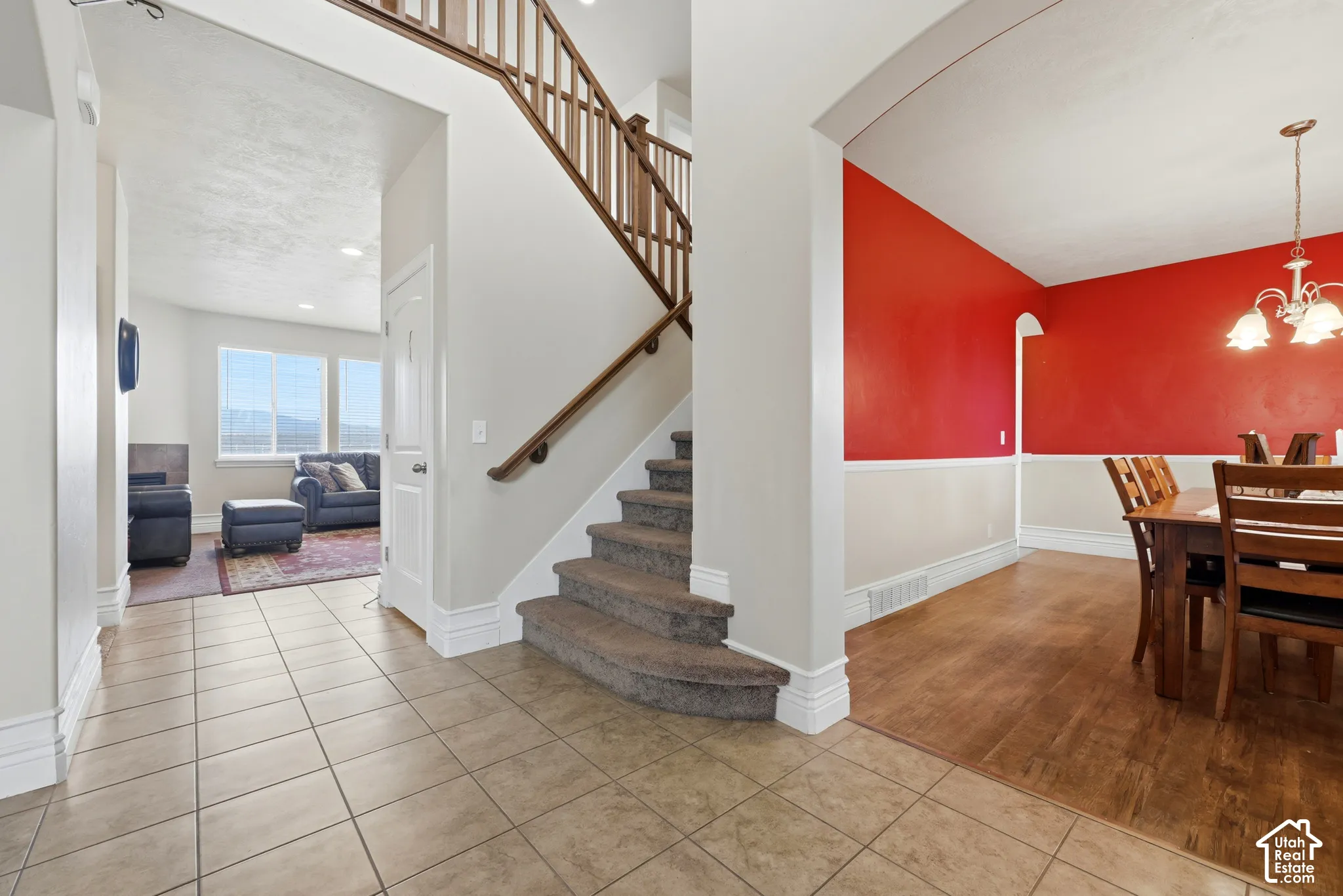 Foyer featuring tile flooring, staircase with wood railings, wood-finish flooring, and a multi-arm chandelier