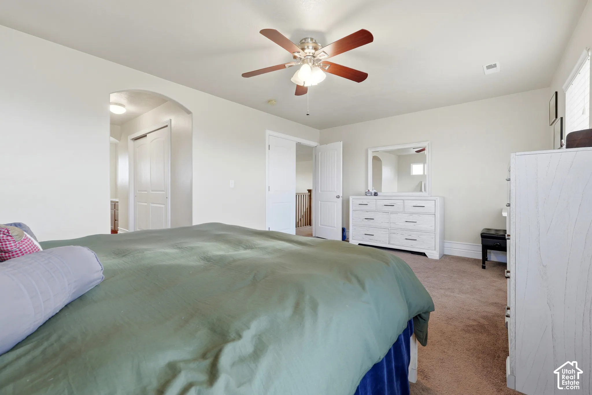 Neutral wall tones, arched interior passage, and a five-blade ceiling fan with integrated light fixture