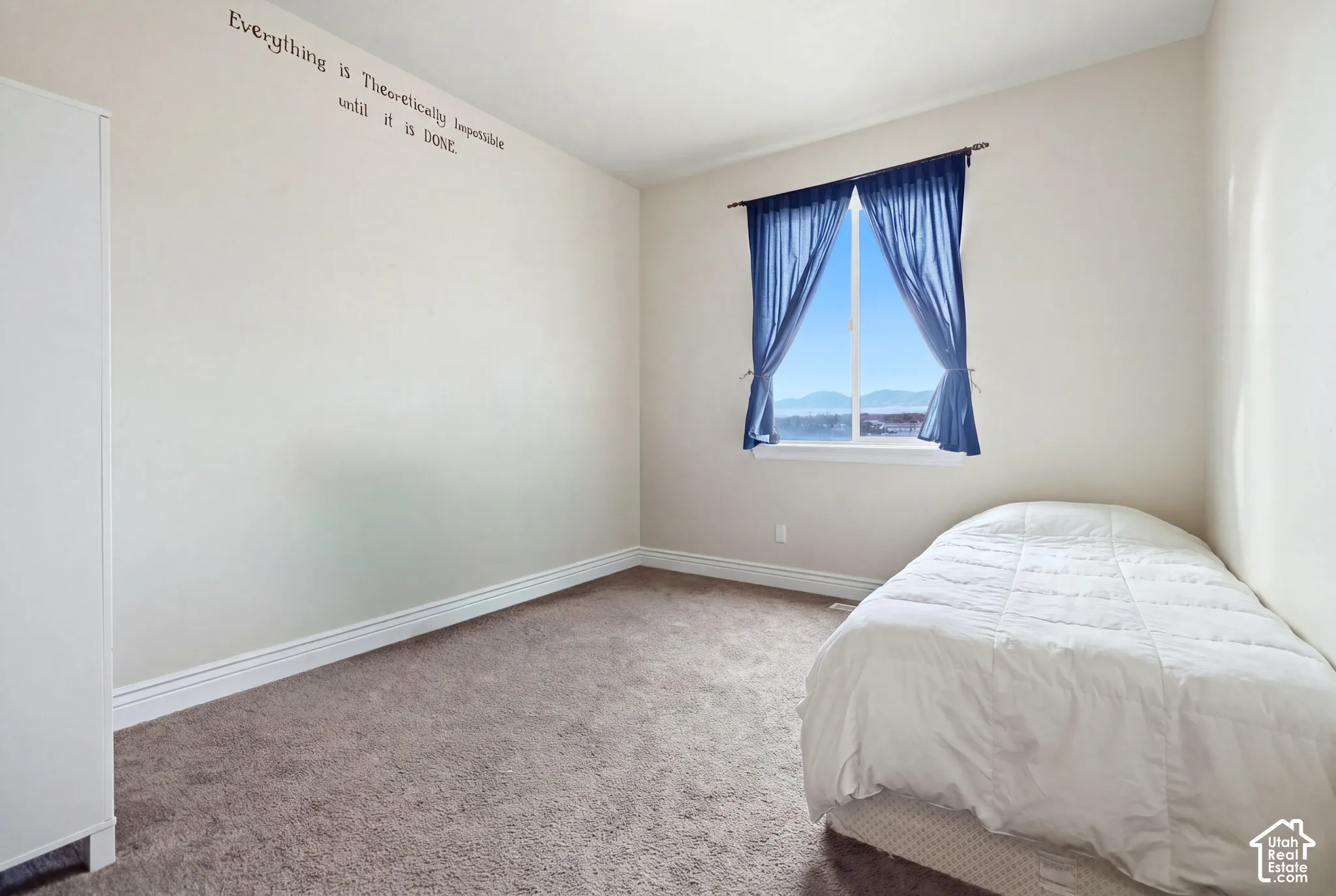 Neutral-toned interior space featuring neutral wall-to-wall carpeting and a single pane window with a mountain backdrop