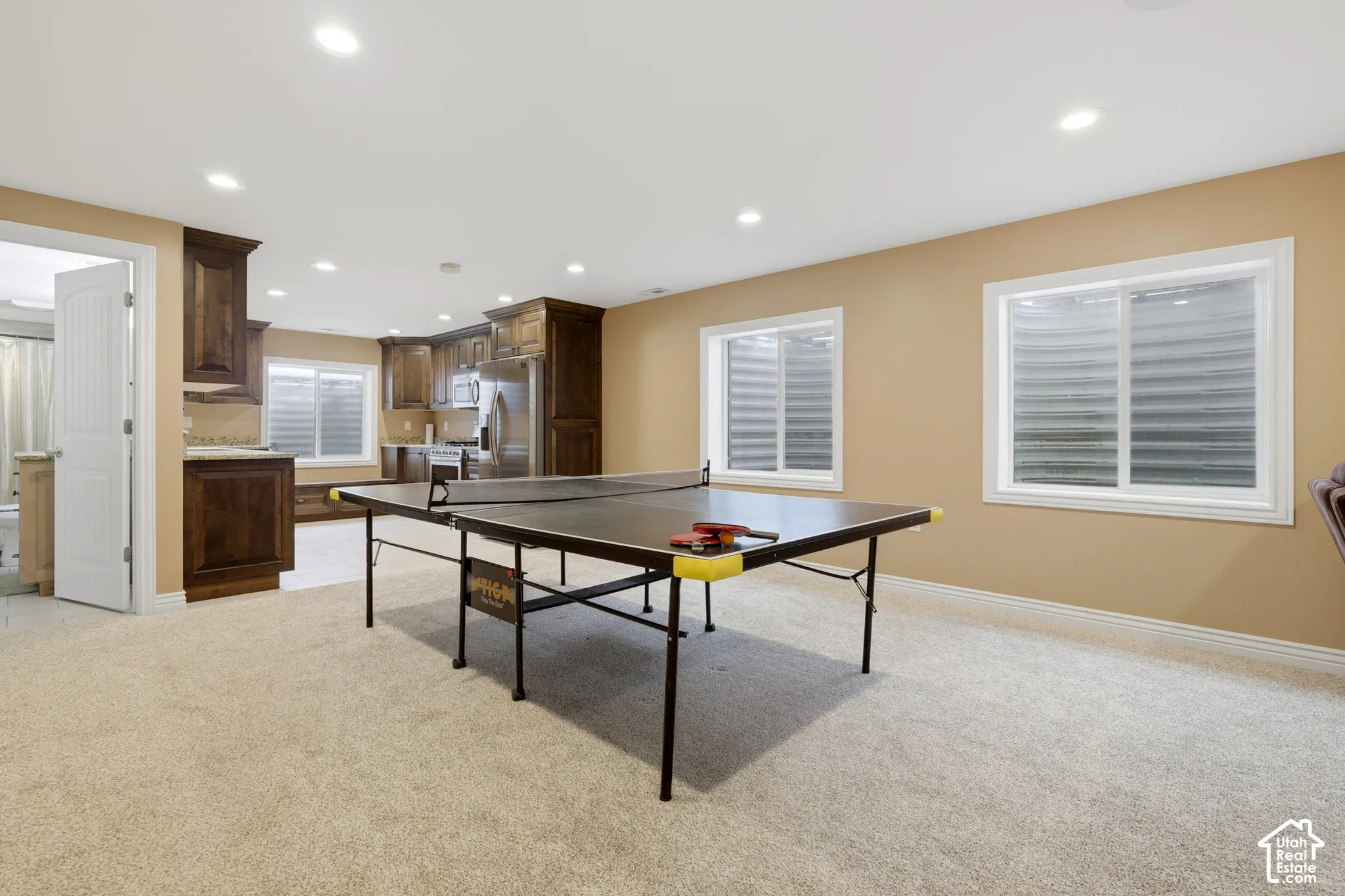 Finished space featuring recessed lighting, carpeting, custom dark wood cabinetry, stainless steel appliances, and two egress-style windows