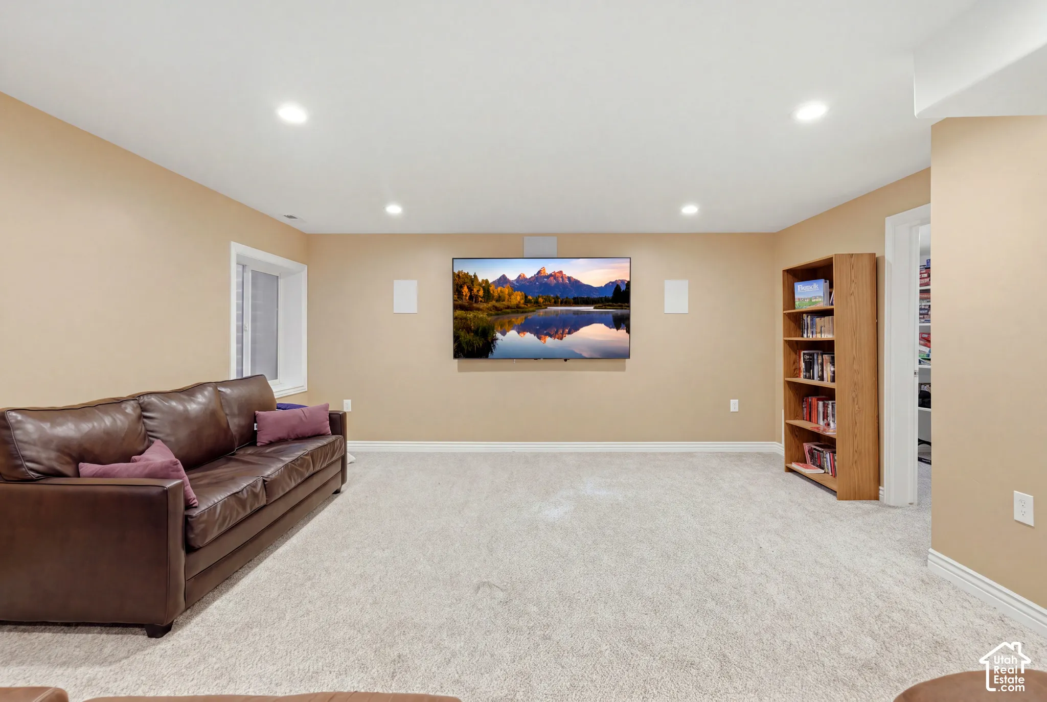 Neutral interior space featuring recessed ceiling lighting, wall-to-wall carpeting, and a built-in wooden shelving unit
