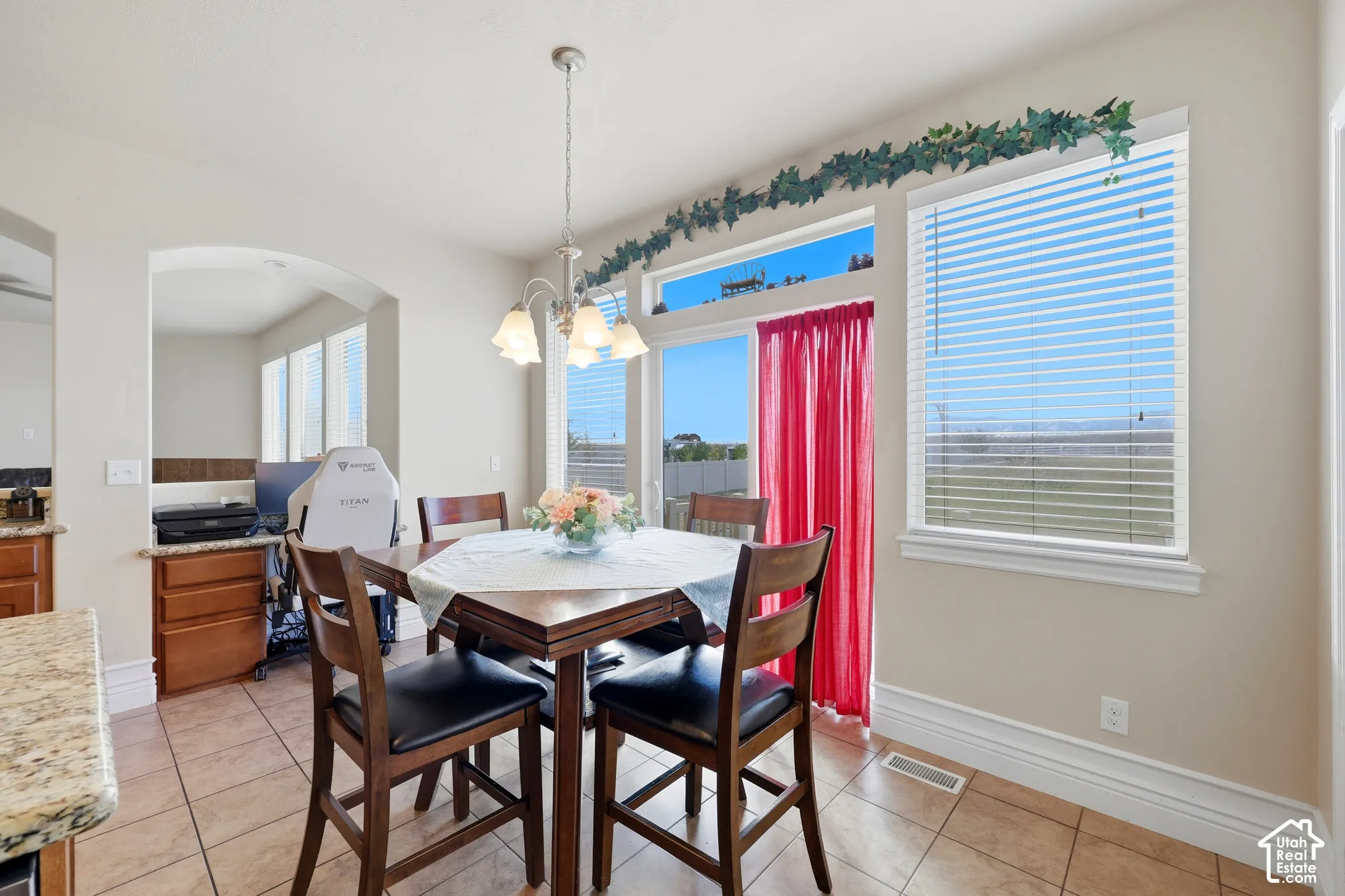 Dining area featuring tile flooring, a multi-light chandelier, a built-in wooden desk, and large windows with transom panels