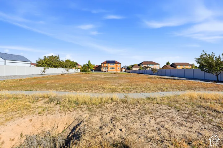 Expansive parcel of land featuring perimeter vinyl fencing and a concrete sidewalk