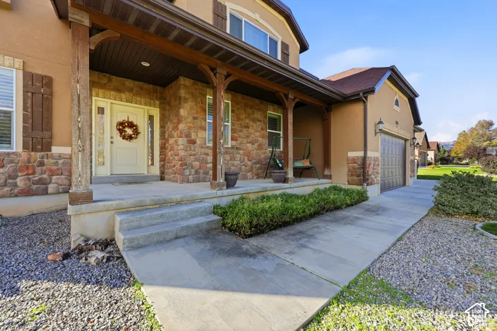 Stucco and stone veneer exterior featuring a covered front porch, timber support posts, and an attached multi-car garage