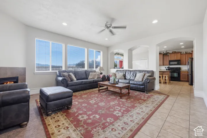 Living area featuring tile flooring, three large windows, a fireplace with tile surround, recessed lighting, and arched architectural openings
