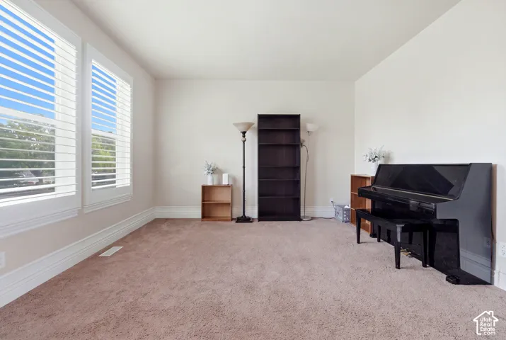 Neutral-toned interior space featuring dual windows with integrated plantation shutters and wall-to-wall carpeting