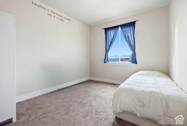 Neutral-toned interior space featuring neutral wall-to-wall carpeting and a single pane window with a mountain backdrop