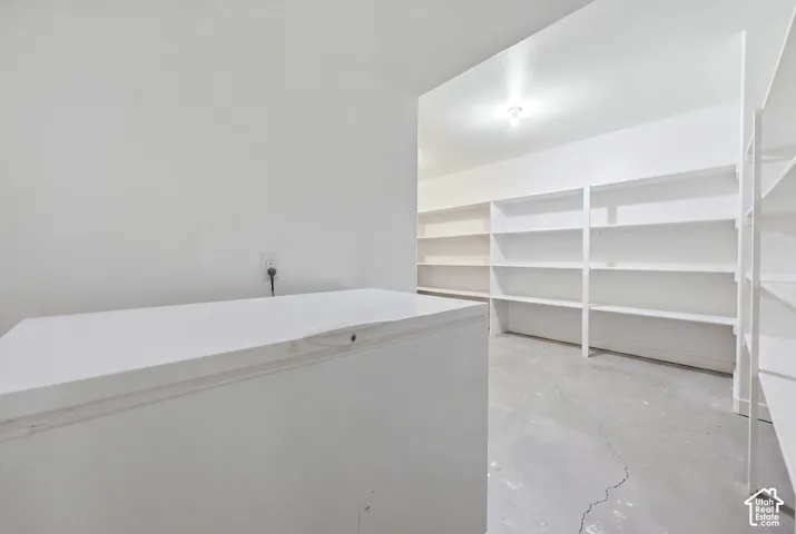 Storage area featuring built-in white shelving and concrete flooring