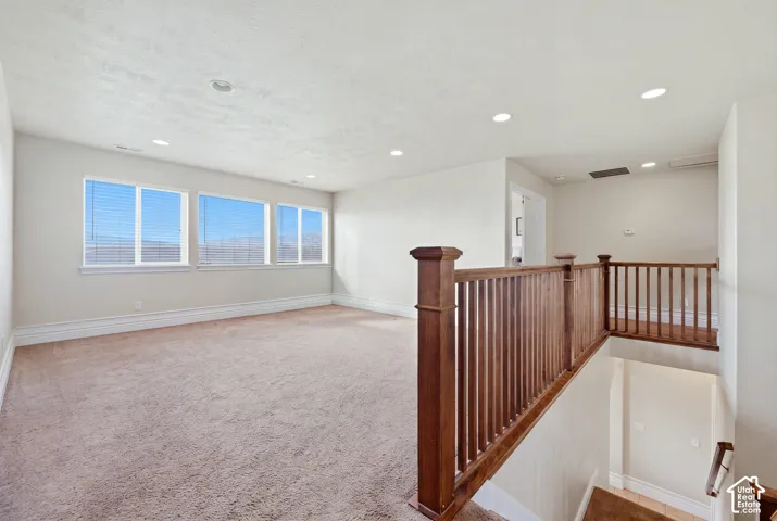 Open floor plan featuring carpeting, recessed lighting, multiple windows, and a wood railing