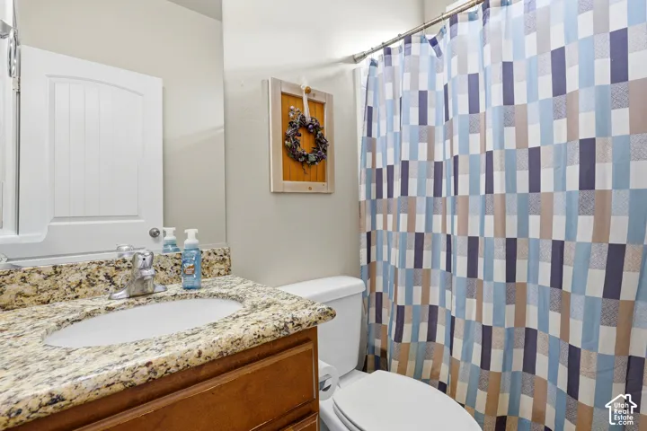 Bathroom featuring a wood-finish vanity with a stone-composite countertop, integrated oval sink, and polished chrome faucet