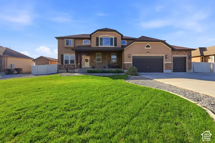 Stucco and stone veneer exterior featuring a three-car garage, covered entryway, and asphalt shingle roof