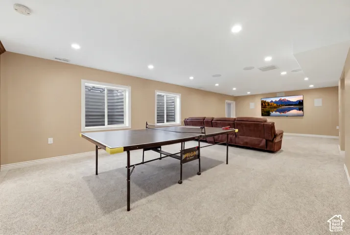 Open-concept room featuring neutral wall paint, wall-to-wall carpeting, recessed ceiling lighting, integrated ceiling speakers, and double egress windows