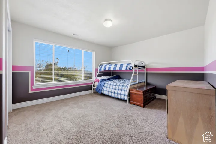 Neutral wall paint with decorative horizontal accent trim, carpeted flooring, and a large horizontal window with integrated blinds