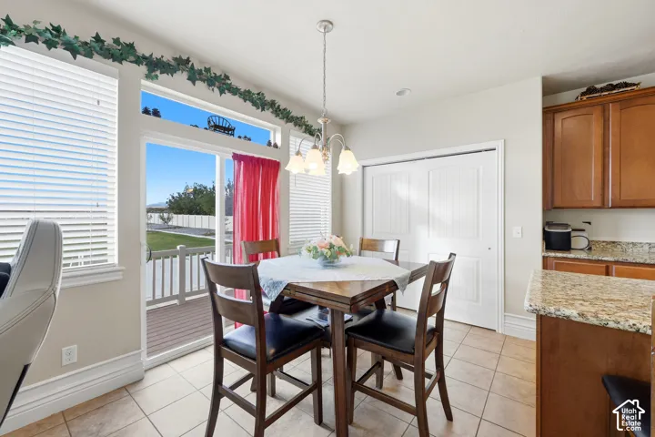 Eat-in area featuring ceramic tile flooring, built-in wooden cabinetry, stone-finish countertops, sliding glass door with transom window, and an attached multi-light chandelier