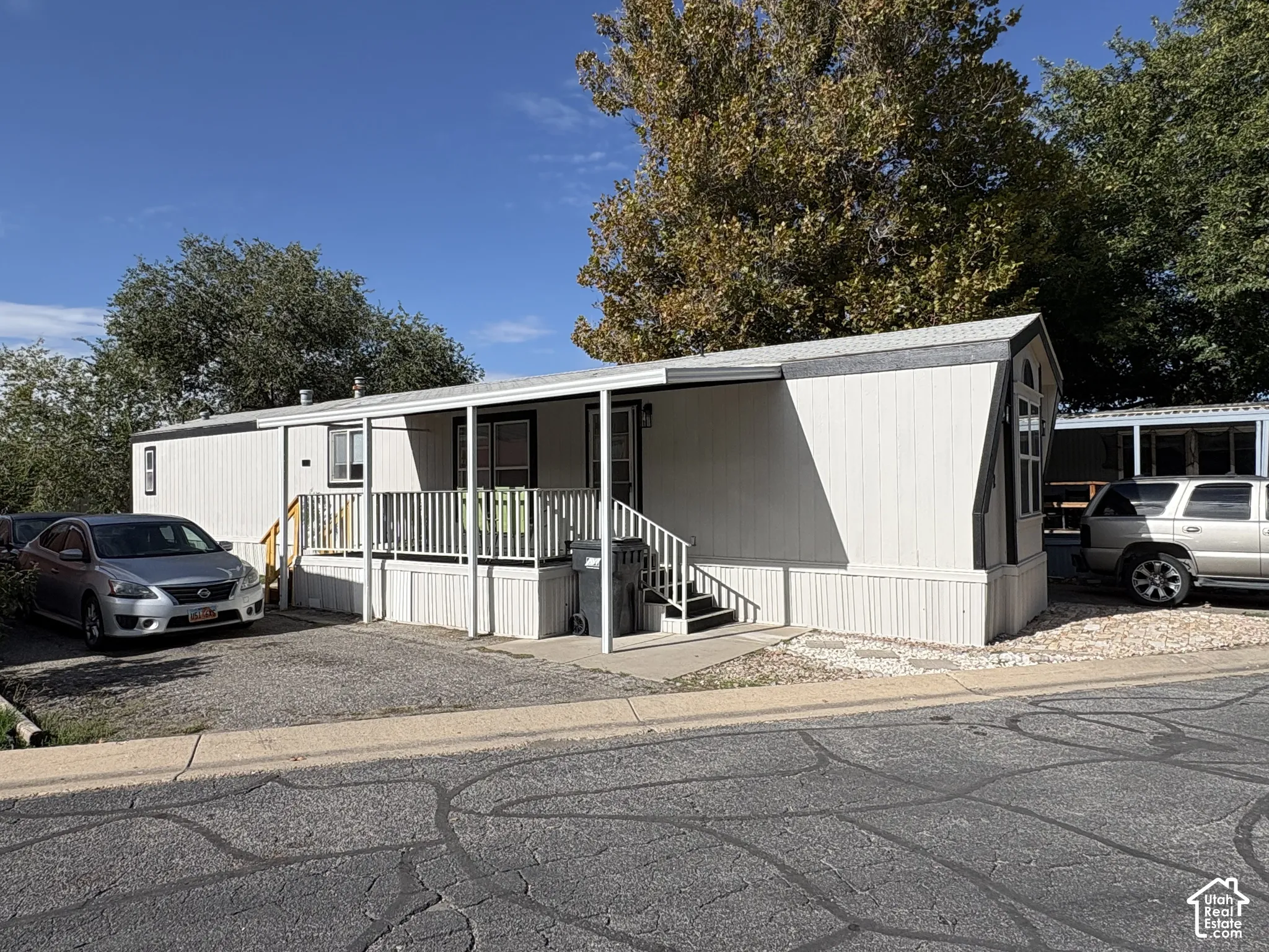 Light-colored exterior siding with contrasting trim, covered front porch, and gravel driveway