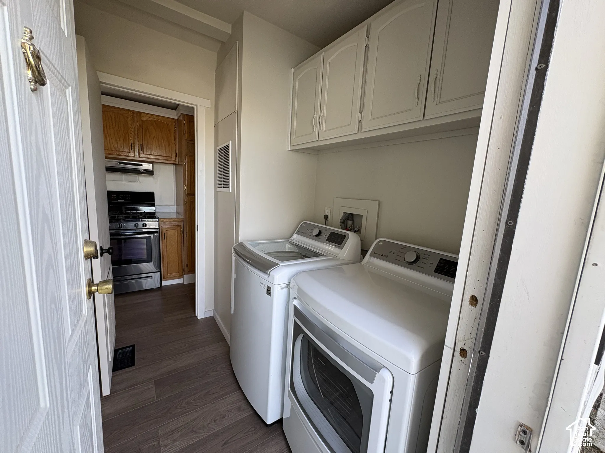Laundry room featuring overhead cabinetry, wood-finish flooring, and wall-mounted utility hookups