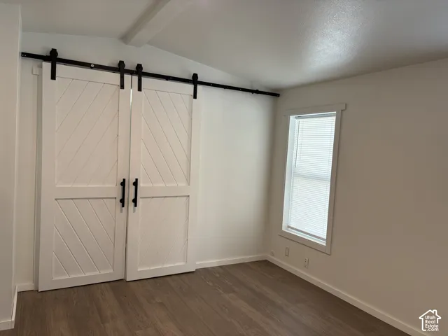 Double white barn doors with black sliding hardware and handles, paired with wood-finish flooring and a single vertical window