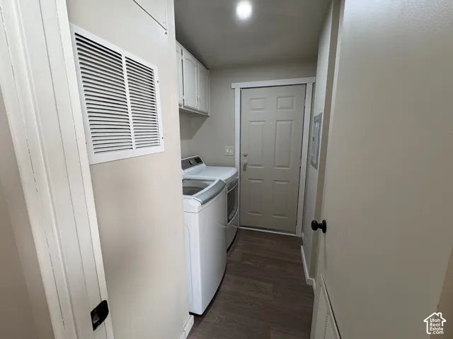 Utility room featuring wood-finish flooring, white upper cabinetry, and a six-panel exterior door