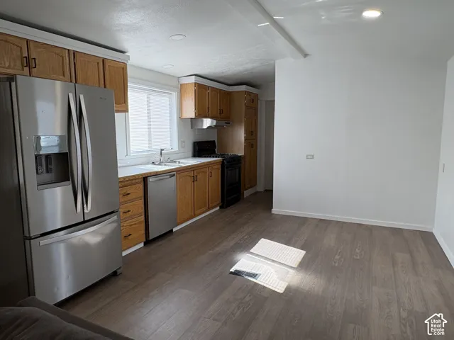 Kitchen featuring wood cabinetry, stainless steel appliances, wood-finish flooring, and recessed ceiling lighting